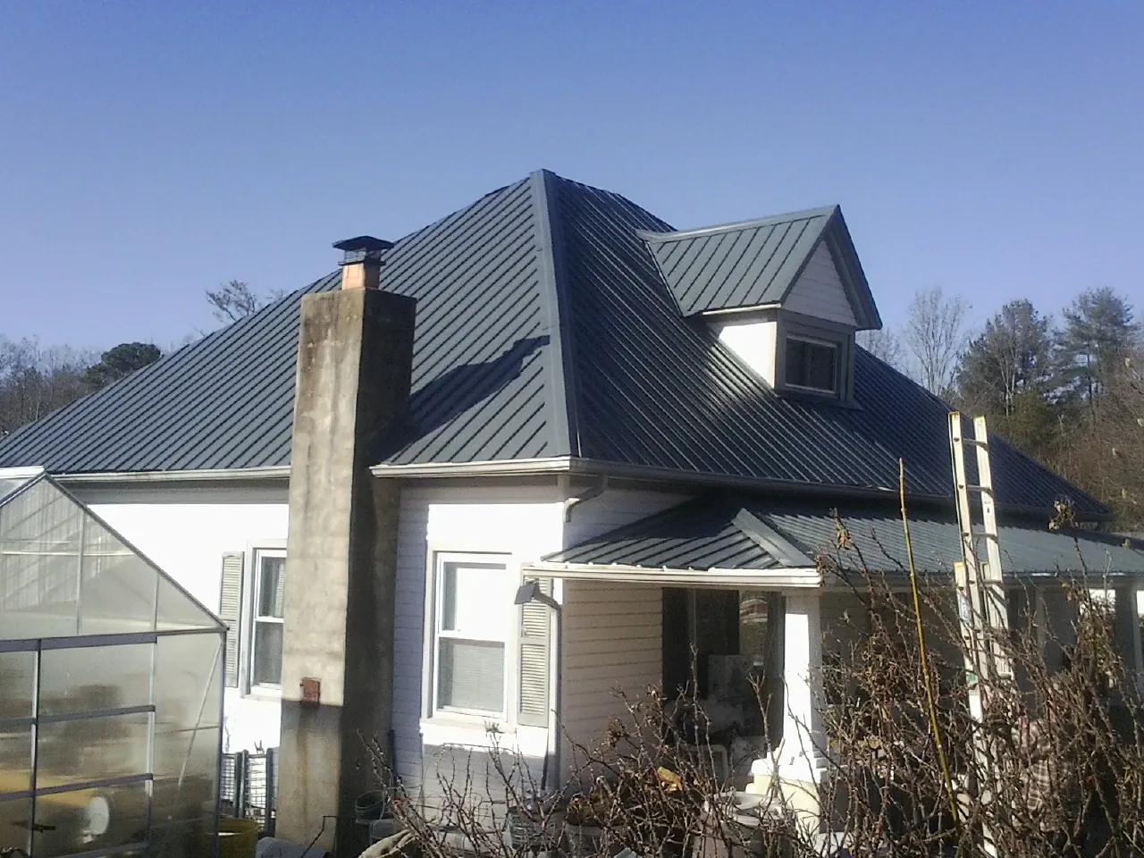 Dark blue standing seam metal roof on a white farmhouse with dormer — Slate & Tile Roof Repair by Roofing Brothers in Wyandotte