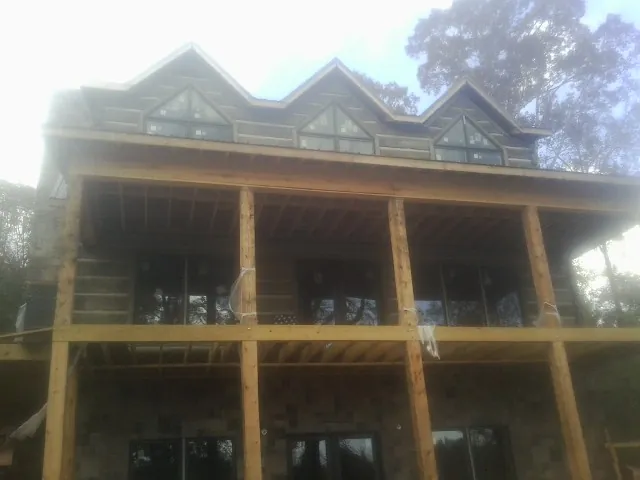 Dormers and porch framing on a large log home under construction — Roof Coating work by our crew in Wyandotte
