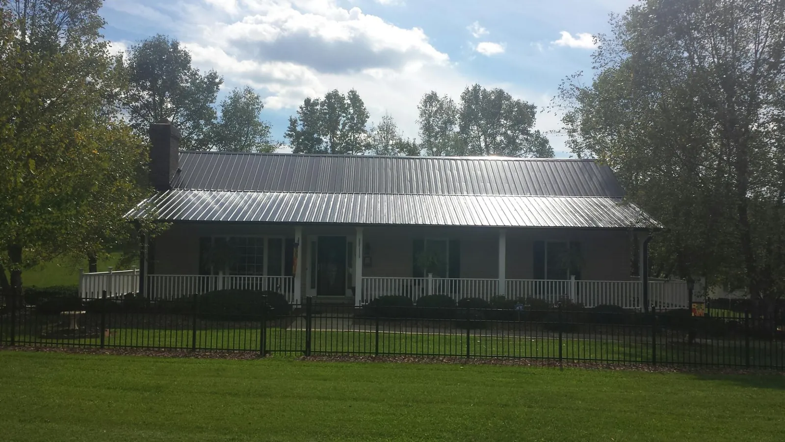 Gray metal roof on a brick ranch with a full width front porch — Gutter Guard Installation work by our crew in Wyandotte