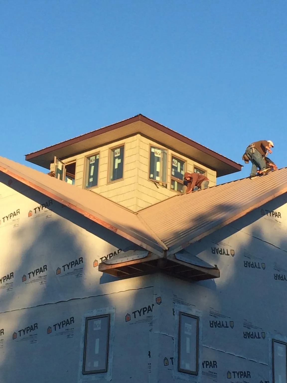 Roofers working around a rooftop cupola on a new metal roof at sunset — Roof Waterproofing in Wyandotte by Roofing Brothers